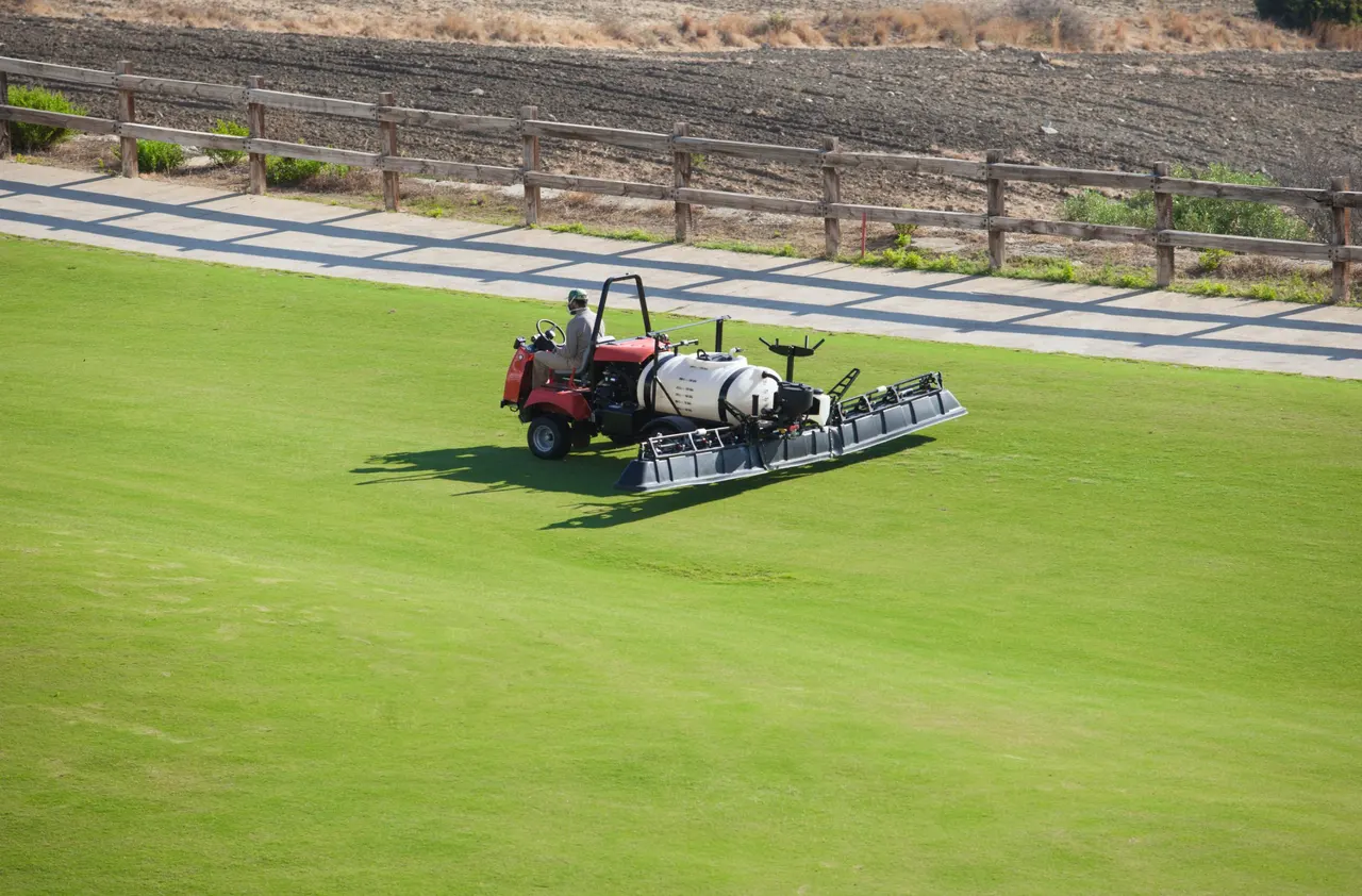 Turf boom sprayer applying a spray treatment across a golf course fairway